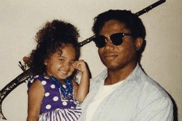 Stevanna Jackson in a blue baby gown smiling with her father in a white t-shirt, denim shirt, and black goggles.